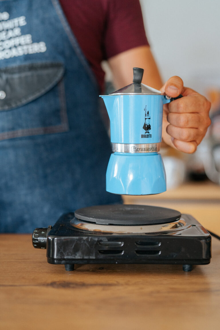 Idealne espresso. Barista ustawia kawiarkę na palniku elektrycznym