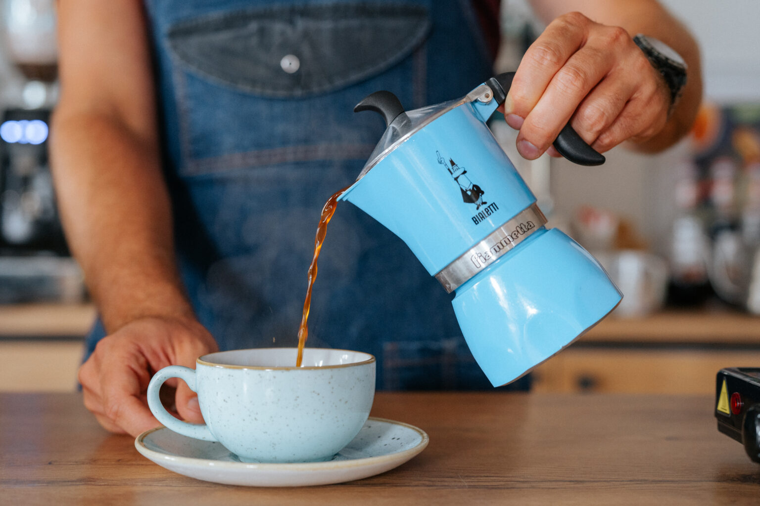 Barista nalewa kawę z kawiarki do filiżanki